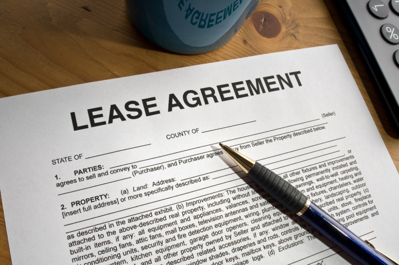 A commercial lease agreement with a pen placed beside it. The image suggests that the document is being prepared or reviewed for signing, emphasizing the legal commitment between a lessor and lessee regarding a business property.