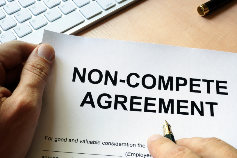 A person holding a non-compete agreement with a pen, emphasizing the importance of signing a non-compete agreement in Texas to protect business interests and trade secrets.