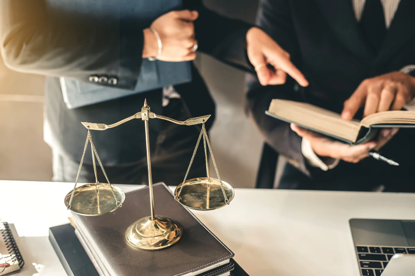 Two professionals in a meeting, discussing terms in a contract with reference to their business partner relationship, possibly addressing legal requirements or negotiations.