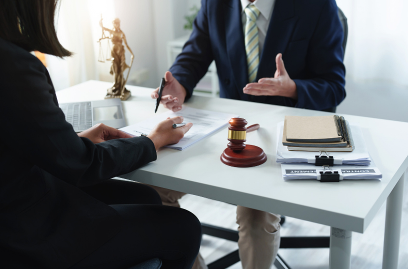 A consultation between a lawyer and a client, with legal documents on the table. This scene could involve reviewing contract defenses, such as fraud, duress, or lack of capacity, in the context of a business or legal dispute.