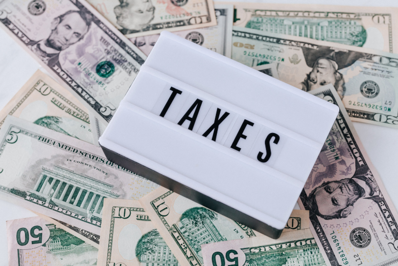 A sign reading "TAXES" surrounded by cash, representing the tax considerations and financial steps involved in understanding how to dissolve an LLC.