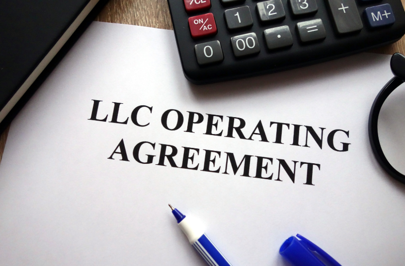 A close-up of an LLC Operating Agreement document, with a pen, calculator, and notebook on the side. This image symbolizes the documentation and agreements involved in the formation and operation of an LLC, an essential element for clarifying the roles and responsibilities within a business.