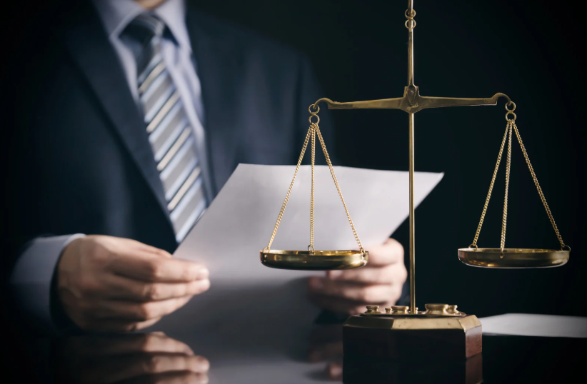 A lawyer holding a paper in front of a scales of justice. This image reflects the legal aspects and formal processes involved in creating and adhering to an LLC Operating Agreement, highlighting its importance in business legal matters.