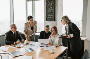 A group of business professionals discussing documents at a table, symbolizing the importance of understanding the differences in structure and benefits between LLC vs corporation.