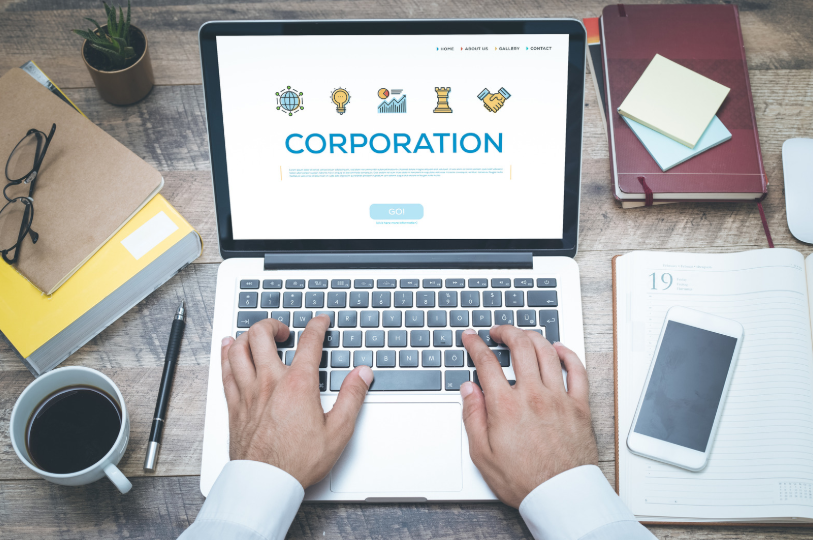 A person typing on a laptop with a "CORPORATION" webpage open, representing the research and comparisons made between LLC vs corporation when forming a business entity.