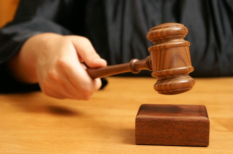 A judge in a courtroom using a gavel, representing the authority to rule on motions, such as a motion to set aside a default judgment, which requests that a previous judgment be overturned or reconsidered.