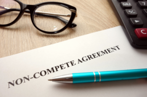 A non-compete agreement document is shown with a pen and glasses. This represents the signing process of a non-compete agreement, which restricts individuals from engaging in certain business activities post-employment, ensuring business protection.