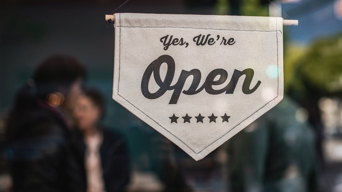 A "Yes, We're Open" sign displayed in a storefront window, signaling that a sole proprietorship business is ready to serve customers and operate freely.