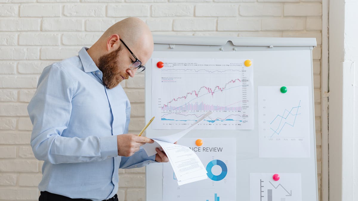 A professional reviewing financial data on a whiteboard, representing the responsibility of managing all aspects of a sole proprietorship, including finances and business strategy.