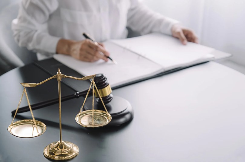 A person reviewing legal documents in the presence of a gavel and scales of justice. The image signifies the legal proceedings that may arise under the Texas Deceptive Trade Practices Act when consumer rights are violated through fraudulent actions.