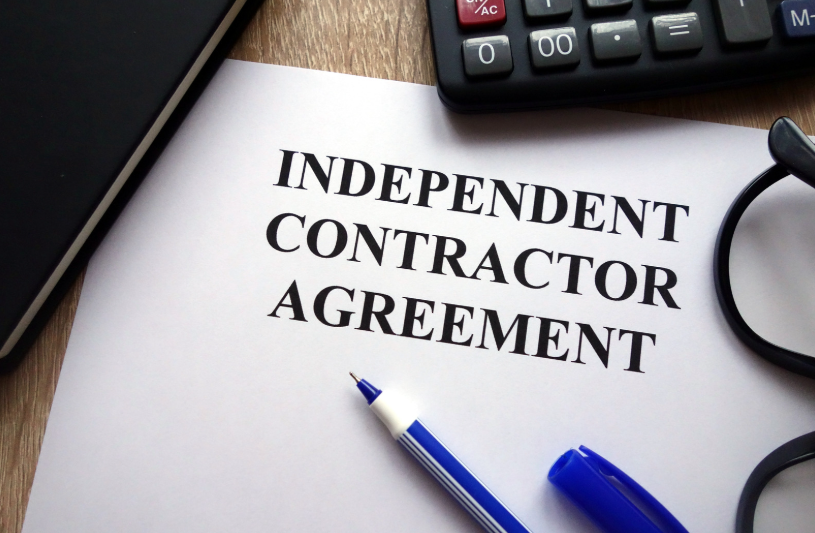 A close-up of an Independent Contractor Agreement document, pen, calculator, and glasses. This symbolizes the legal framework surrounding independent contractors in Texas, with a specific focus on the agreement structure that outlines terms under Texas independent contractor laws.