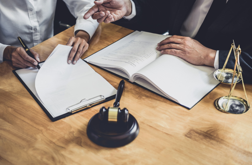 Two individuals discussing over a document with a gavel and scales of justice in the background. This image indicates legal consultations and agreements under Texas independent contractor laws, showcasing the importance of legal expertise when navigating contractor arrangements in Texas.