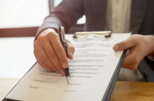 A person signing an agreement, symbolizing the legal implications of tortious interference, where one party wrongfully disrupts an existing contract or business relationship.