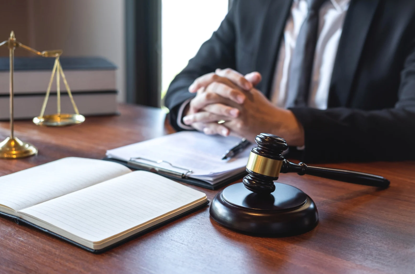 A lawyer discussing legal matters at a desk with a gavel, illustrating the process of addressing tortious interference, where one party unlawfully interferes with another’s contract or business relationship.