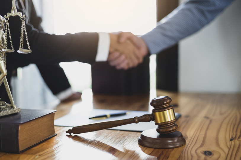 A business litigation lawyer shaking hands with a client, symbolizing a successful resolution or settlement in a business dispute handled by the lawyer.