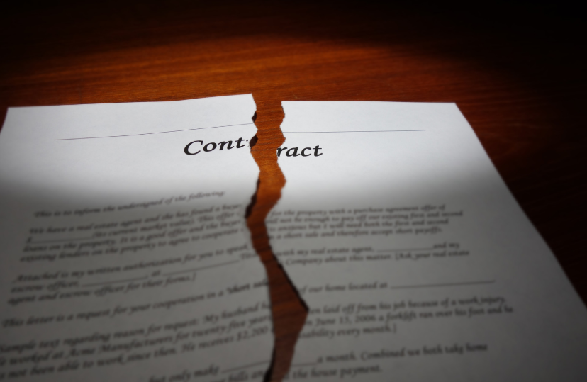 Torn contract on a wooden desk symbolizing a legal dispute, ideal for topics related to breach of contract attorney.