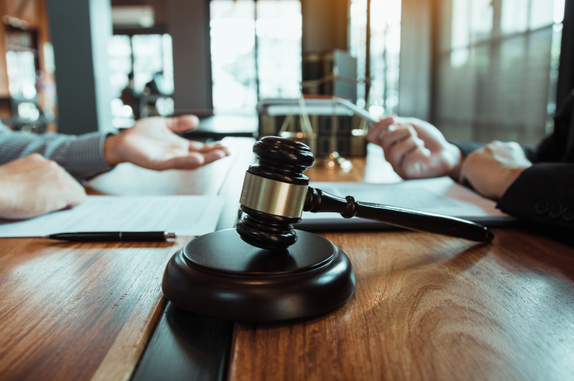 Gavel on a desk with two individuals in discussion, symbolizing legal negotiations related to a business litigation attorney.