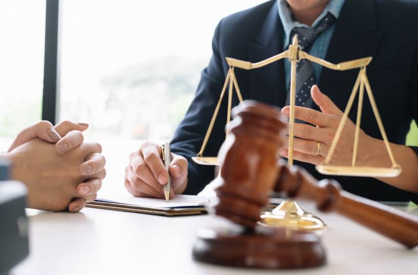 Close-up of a legal consultation with scales of justice and a gavel on the desk, symbolizing the role of a securities lawyer.